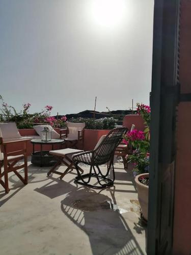a patio with two chairs and tables and flowers at CASA DEI MELOGRANI at Vourlidia Leros in Vromolithos