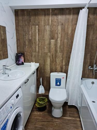 y baño con aseo, lavabo y lavadora. en Апартаменты в центре, в новом доме, en Almaty