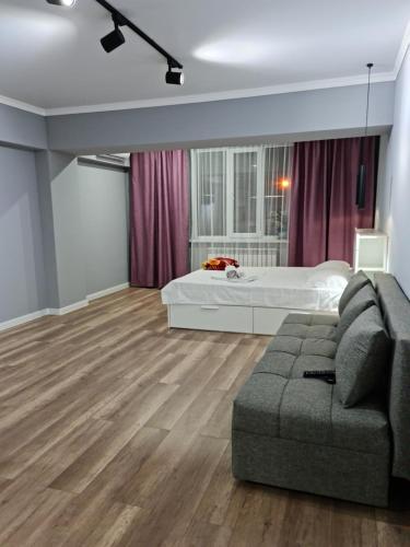 a living room with a bed and a couch at Апартаменты в центре, в новом доме in Almaty