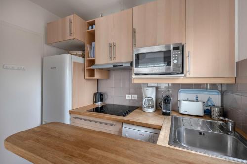 une petite cuisine avec un évier et un micro-ondes dans l'établissement À 300m de la plage, appartement pour 4, à La Baule