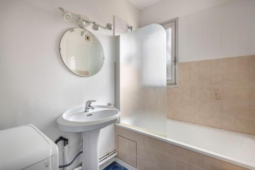 a white bathroom with a sink and a mirror at À 300m de la plage, appartement pour 4 in La Baule