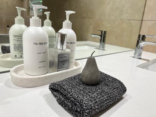 a bathroom counter with four bottles of soap and a sponge at Carramah Noosa Heads apartment in Noosa Heads