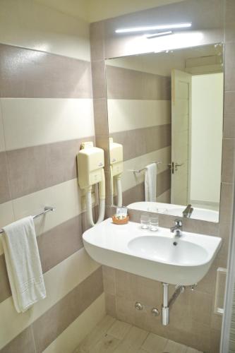 a bathroom with a sink and a mirror at Ouril Hotel Julia in Santa Maria