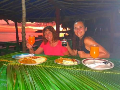 Mana Lagoon Backpackers في جزيرة مانا: يجلس رجل وامرأة على طاولة مع أطباق من الطعام
