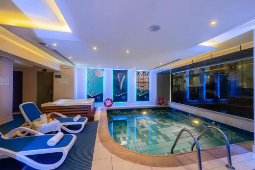 فندق بلو دايموند جدة في جدة: مسبح في غرفة الفندق مع كراسي ومسبح