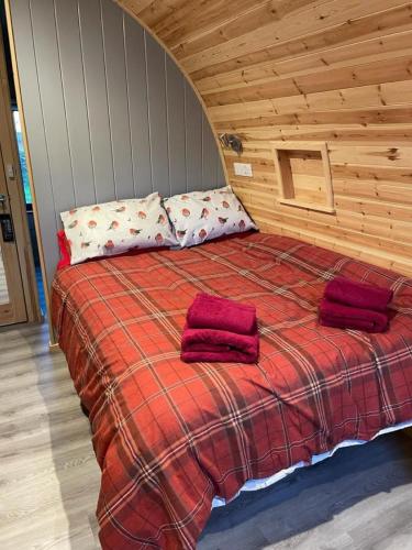 a bedroom with a bed with two red pillows on it at Glamping Pods in Milngavie