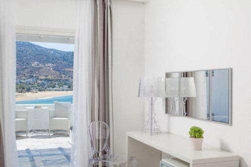 a white room with a table and a view of the ocean at Ios Palace Hotel & Spa in Mylopotas