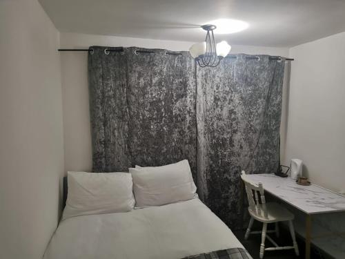 Schlafzimmer mit einem Bett, einem Schreibtisch und einem Tisch in der Unterkunft Ella's Place in Luton