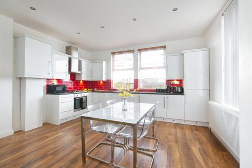 a kitchen with white cabinets and a glass table at spacious apartment close to city centre with free secure parking in Leeds