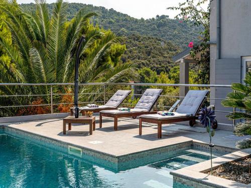 a swimming pool with two lounge chairs next to a house at Villa Angela in Lastovo