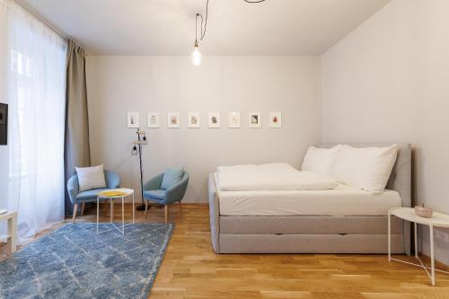 a white bedroom with a bed and a blue chair at Vienna City Apartments Krongasse in Vienna