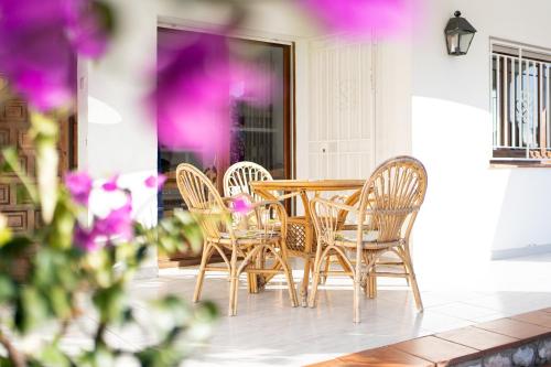 a table and chairs on a patio with purple flowers at Coma-ruga in El Vendrell
