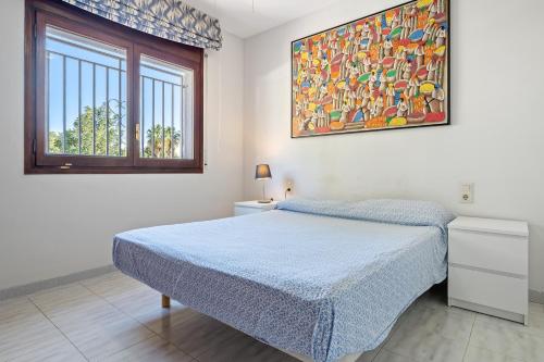 a bedroom with a bed and a painting on the wall at Coma-ruga in El Vendrell