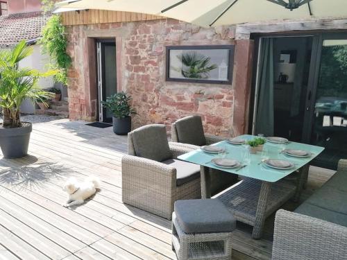 een tafel en stoelen en een hond op een patio bij Du côté de chez Pam in Beblenheim