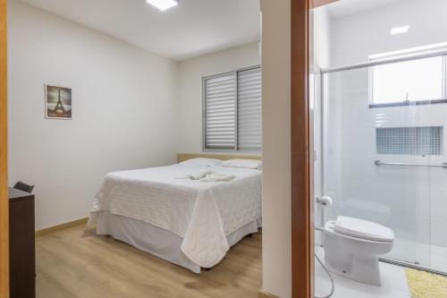 a white bedroom with a bed and a toilet at Hotel Lisbor in Francisco Beltrão