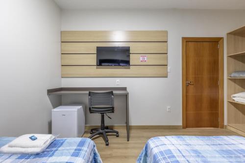 um quarto com 2 camas, uma secretária e uma cadeira em Hotel Lisbor em Francisco Beltrão