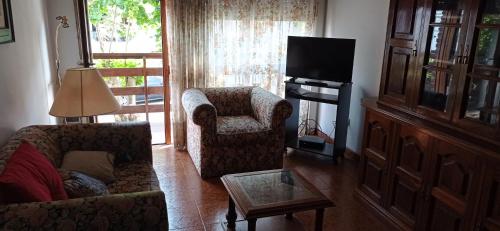 ein Wohnzimmer mit einem Sofa, einem Stuhl und einem TV in der Unterkunft Playa Grande hermoso departammento in Mar del Plata