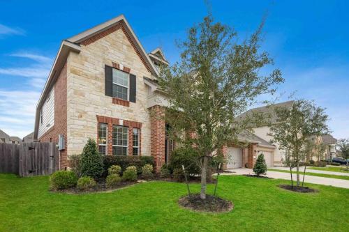 a brick house with a tree in the yard at Houston House~Sleeps 16~Arcade Style Game Room in Deer Park
