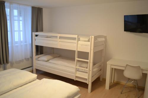 a white bunk bed in a room with a desk at Platia - rooms in Günzburg