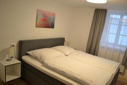 a bed with white pillows and avertisement at Platia - rooms in Günzburg