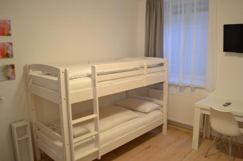 a white bunk bed in a room with a desk at Platia - rooms in Günzburg