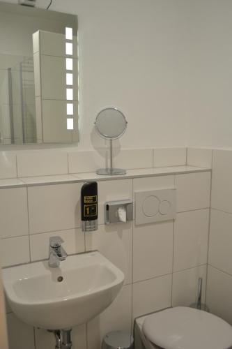 a bathroom with a sink and a toilet and a mirror at Platia - rooms in Günzburg