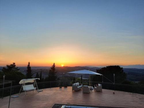 a view of a sunset from a patio with chairs and an umbrella at Villa Tutti i colori del Chianti in Linari