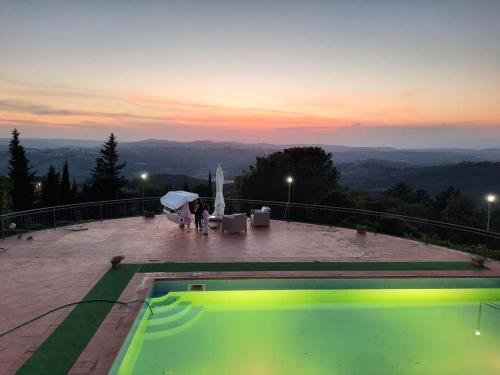una pareja de pie bajo una sombrilla junto a una piscina en Villa Tutti i colori del Chianti, en Linari