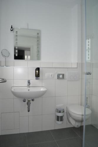 a white bathroom with a sink and a toilet at Platia - rooms in Günzburg