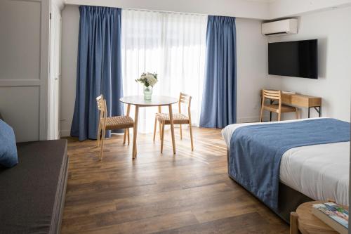 a hotel room with a bed and a table and chairs at Résidence Carlton - Rénovée avec Piscine in Beaulieu-sur-Mer