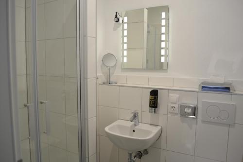 a white bathroom with a sink and a mirror at Platia - rooms in Günzburg