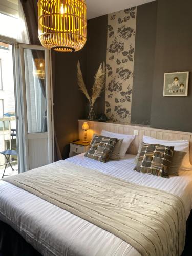 Un dormitorio con una cama grande y una lámpara de araña. en Hôtel de charme Equinoxe, en Le Touquet-Paris-Plage