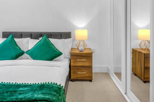 a bedroom with a bed with green pillows and a mirror at One Bedroom Serviced Apartment in Islington in London