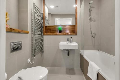 a bathroom with a sink and a toilet and a bath tub at One Bedroom Serviced Apartment in Islington in London