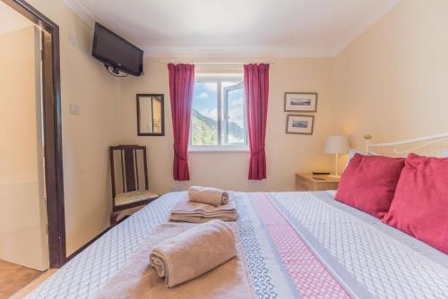 a bedroom with a bed with red pillows and a window at Lavender Cottage Coniston in Coniston