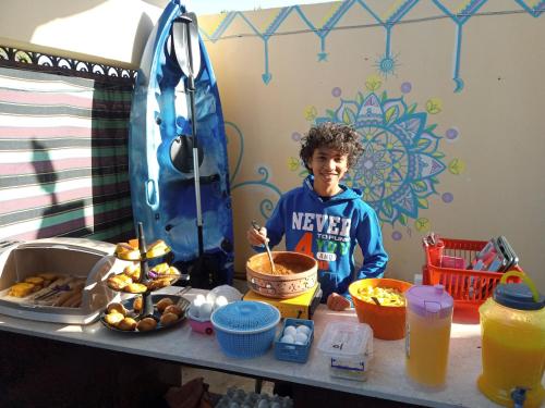 a young boy standing in front of a table with food at Go Inn Backpackers in Aswan