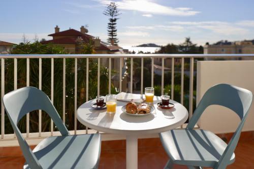 a table with two chairs and a plate of food on a balcony at Résidence Carlton - Rénovée avec Piscine in Beaulieu-sur-Mer