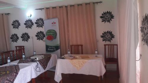 a dining room with two tables and chairs and curtains at Kigezi Gardens Inn in Kabale