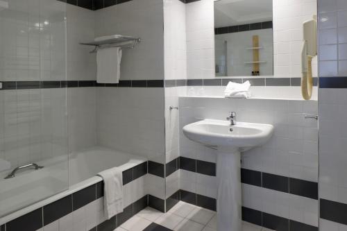 a bathroom with a sink and a bath tub at Résidence Carlton - Rénovée avec Piscine in Beaulieu-sur-Mer