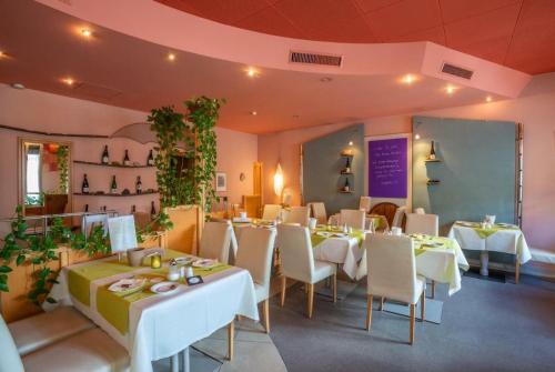 a restaurant with white tables and chairs and plants at Park Hotel in Konz