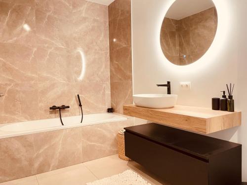 Un baño con lavabo, bañera y espejo. en Luxe appartement Cadzand-Bad, en Cadzand