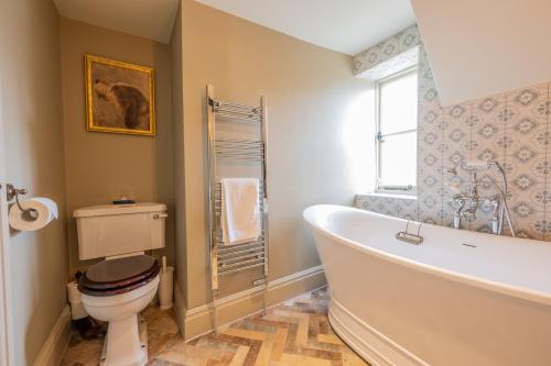 a bathroom with a tub and a toilet and a window at Eliot Arms in Cirencester