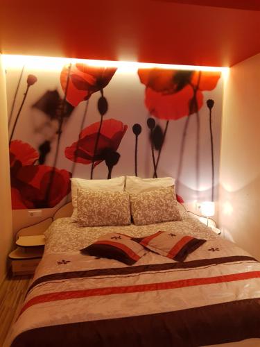 - une chambre avec un lit orné de fleurs rouges sur le mur dans l'établissement Trumpalaikė buto nuoma,apgyvendinimas - bekontaktis įėjimas, à Rokiškis