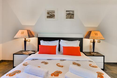 ein Schlafzimmer mit einem Bett mit orangefarbenen Kissen und zwei Lampen in der Unterkunft Falesia Beach A in Albufeira