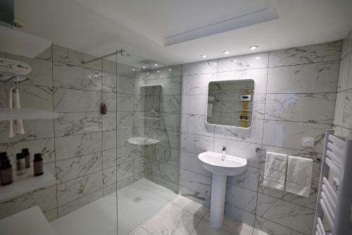 a white bathroom with a sink and a shower at Résidence Carlton - Rénovée avec Piscine in Beaulieu-sur-Mer