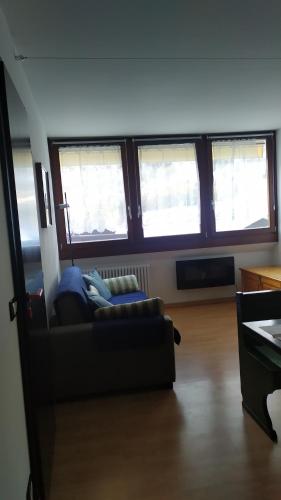 a living room with a couch and three windows at CASA DESIRE' in Piancavallo