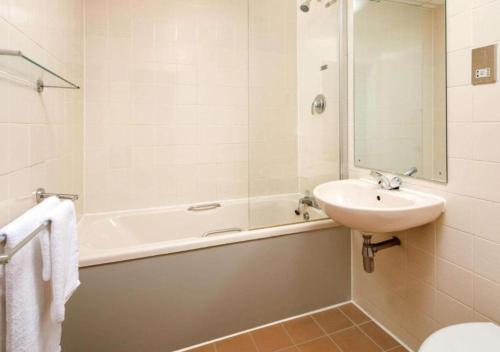 uma casa de banho com um lavatório e uma banheira e um lavatório em Mercure Norwich Hotel em Norwich