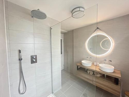 a bathroom with a shower and two sinks and a mirror at No3 Gweek in Gweek