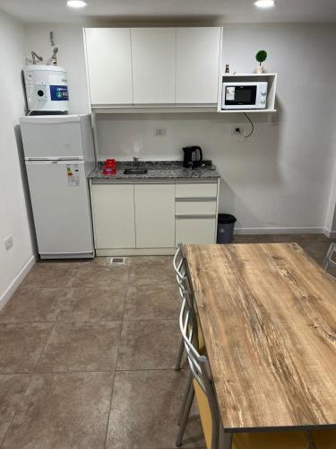 cocina con electrodomésticos blancos y mesa de madera en Departamento guemes C en San Pedro