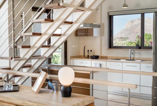 a kitchen with a wooden staircase in a house at Magnifique villa avec piscine au bord de mer in Chorafakia